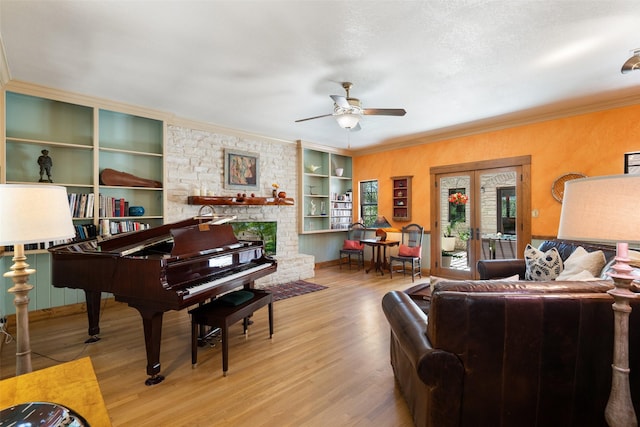 living room with a textured ceiling, ceiling fan, ornamental molding, light hardwood / wood-style floors, and built in features