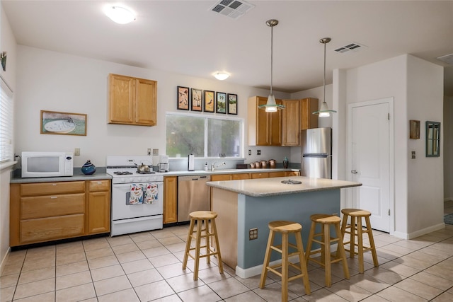 kitchen featuring stainless steel appliances, light tile patterned floors, a breakfast bar, a kitchen island, and decorative light fixtures