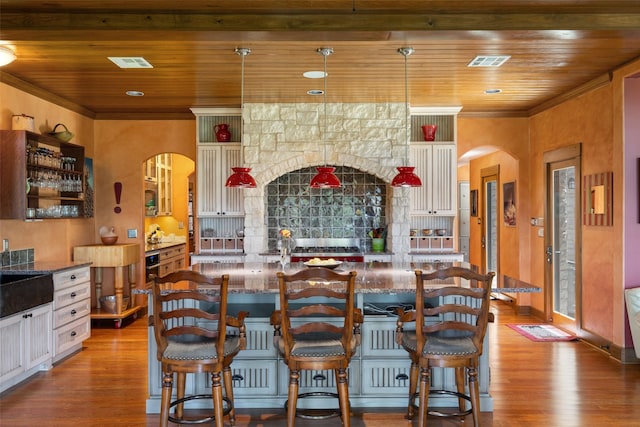 kitchen featuring light hardwood / wood-style floors, decorative light fixtures, wooden ceiling, and a breakfast bar area