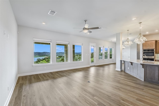 kitchen featuring a kitchen breakfast bar, plenty of natural light, ceiling fan with notable chandelier, double oven, and pendant lighting