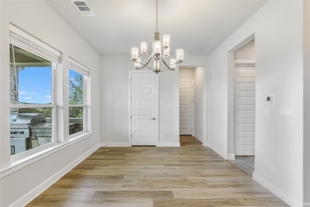 unfurnished dining area featuring light wood-type flooring and a chandelier