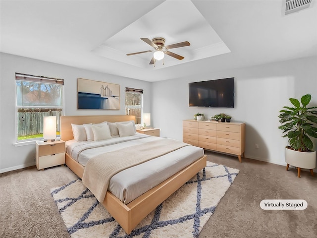 carpeted bedroom with ceiling fan and a tray ceiling