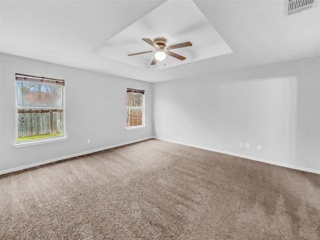 empty room featuring ceiling fan, carpet flooring, and a tray ceiling