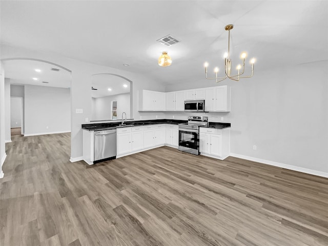 kitchen featuring pendant lighting, light hardwood / wood-style floors, white cabinetry, appliances with stainless steel finishes, and sink