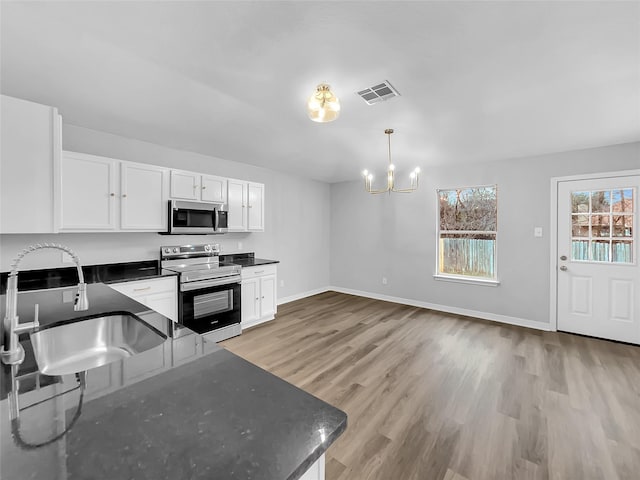 kitchen featuring appliances with stainless steel finishes, pendant lighting, white cabinets, light hardwood / wood-style flooring, and sink