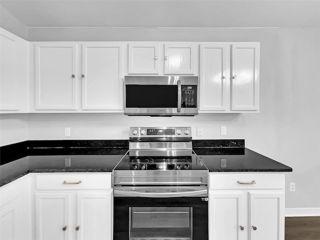 kitchen with stainless steel appliances, dark stone countertops, wood-type flooring, and white cabinetry