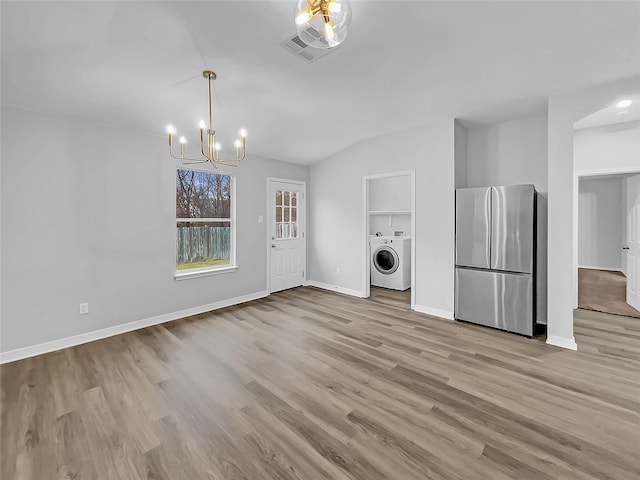 laundry area featuring a notable chandelier, light hardwood / wood-style floors, and washer / clothes dryer