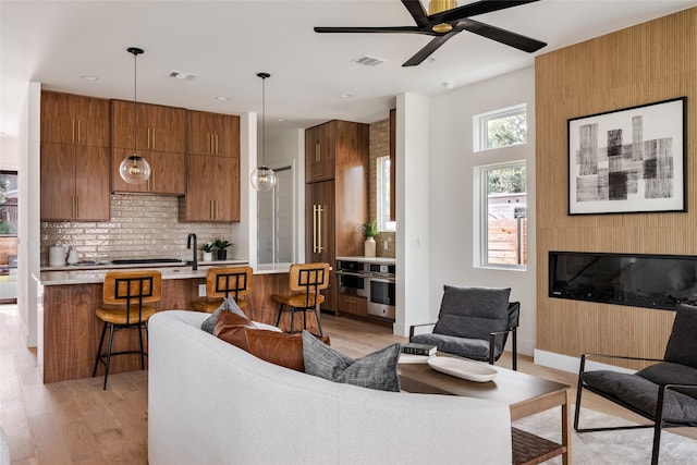 living room featuring ceiling fan, light hardwood / wood-style flooring, and sink