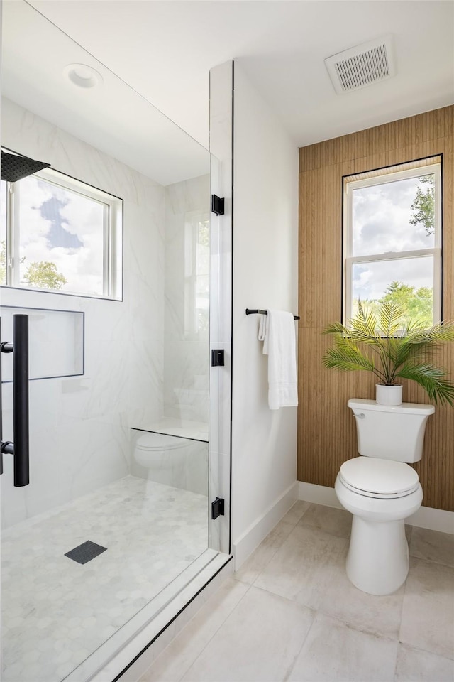 bathroom with a shower with door, tile patterned flooring, and toilet