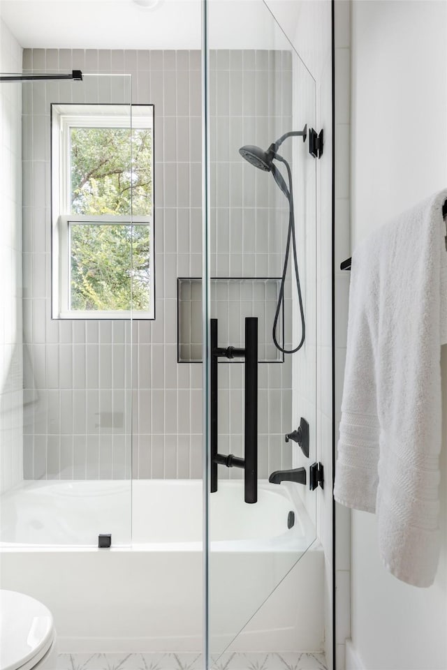 bathroom with bath / shower combo with glass door and toilet