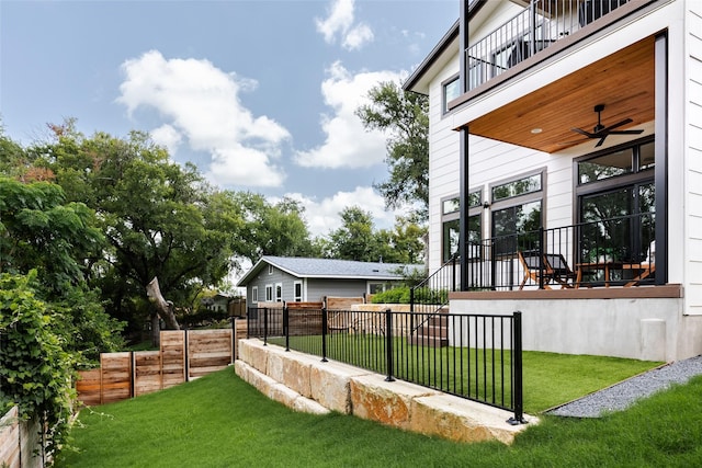 view of yard featuring ceiling fan and a balcony