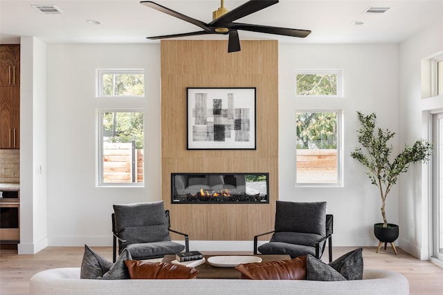 living room with a large fireplace, ceiling fan, and light hardwood / wood-style floors