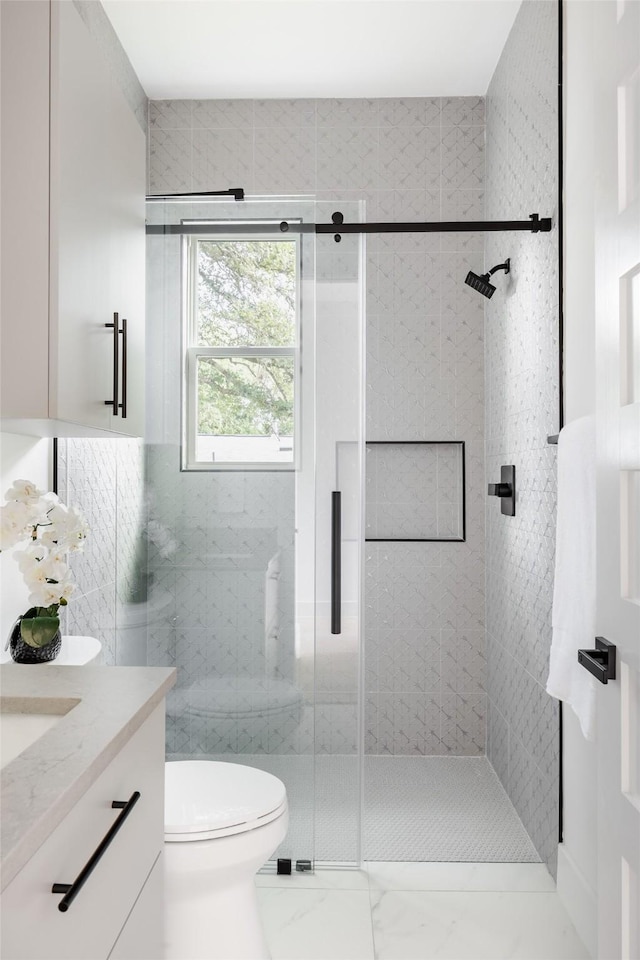 bathroom with toilet, vanity, and a shower with shower door