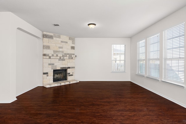 unfurnished living room with hardwood / wood-style flooring and a stone fireplace