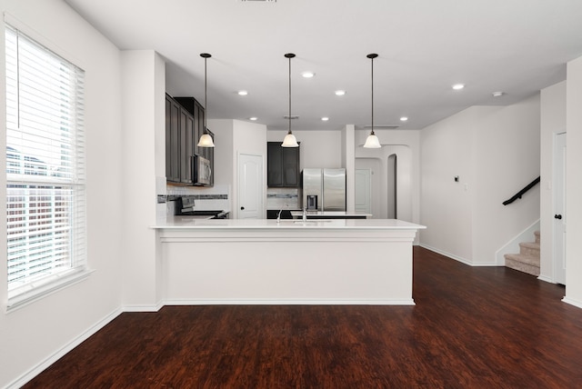 kitchen with stainless steel appliances, plenty of natural light, kitchen peninsula, and hanging light fixtures