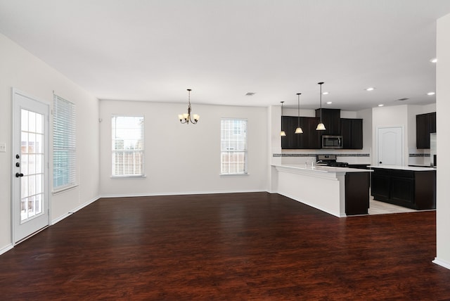 kitchen with kitchen peninsula, backsplash, a chandelier, pendant lighting, and appliances with stainless steel finishes