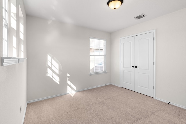 unfurnished bedroom featuring a closet and light carpet