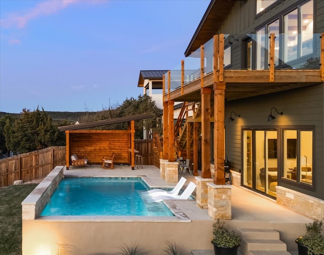 pool at dusk featuring a patio and pool water feature