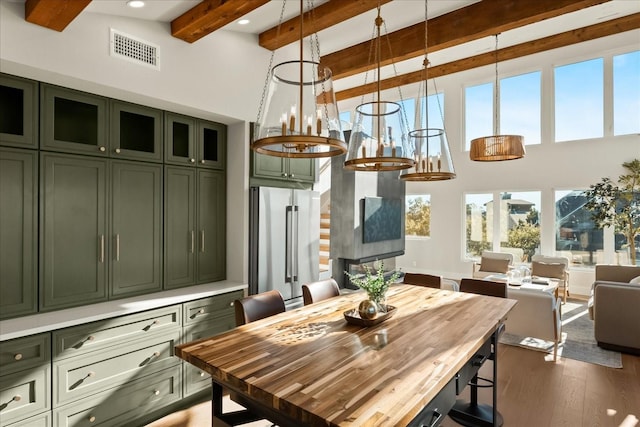 dining space featuring beam ceiling, dark hardwood / wood-style floors, and a towering ceiling