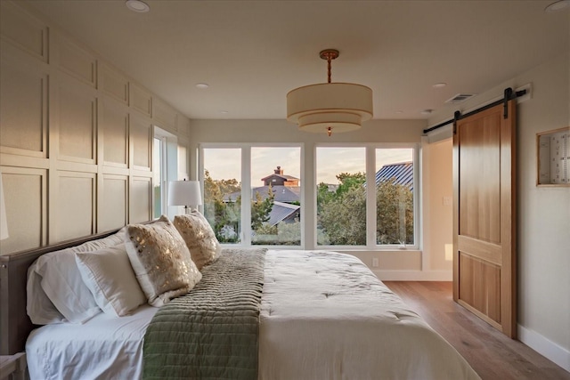 bedroom with light hardwood / wood-style flooring and a barn door