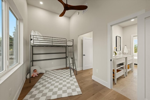 bedroom featuring ceiling fan, light hardwood / wood-style floors, and ensuite bath