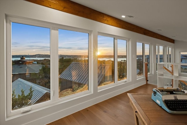 sunroom / solarium featuring beamed ceiling and a water view