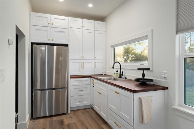 kitchen featuring sink, white cabinets, stainless steel fridge, and wood counters