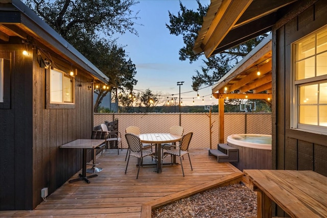 deck at dusk featuring a hot tub