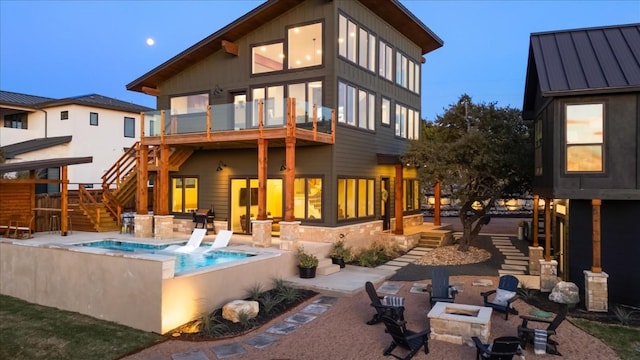 back of house featuring a hot tub, a patio, a balcony, and an outdoor fire pit