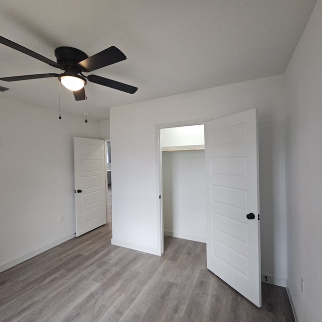 unfurnished bedroom with light wood-type flooring, ceiling fan, and a closet