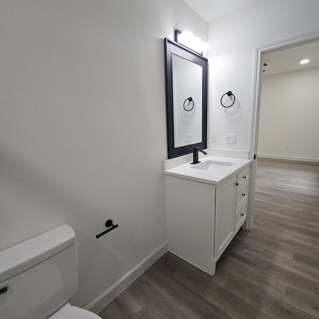 bathroom featuring toilet, vanity, and hardwood / wood-style floors