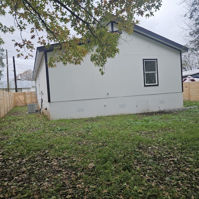 view of side of home with central AC and a yard