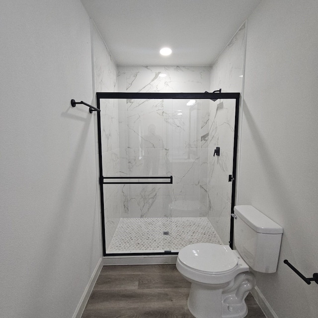 bathroom featuring toilet, a shower with shower door, and hardwood / wood-style floors