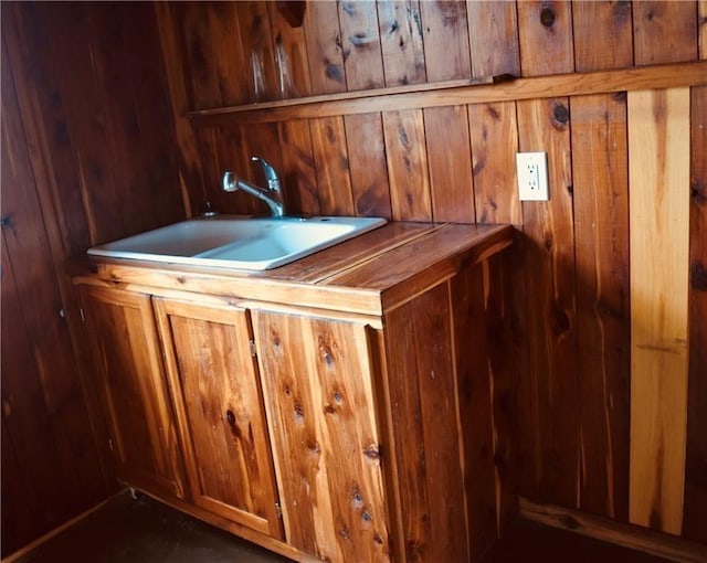 bar featuring sink and wood walls