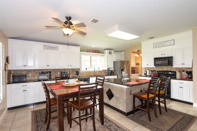 kitchen featuring black appliances, light tile patterned floors, ceiling fan, a kitchen island, and white cabinets