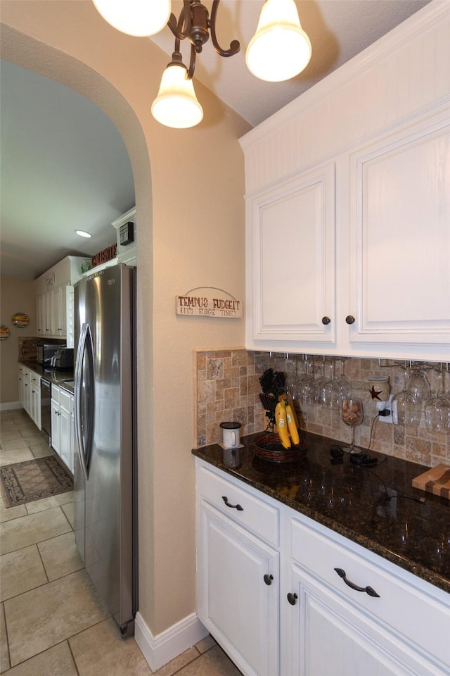 kitchen with dark stone countertops, stainless steel fridge, tasteful backsplash, and white cabinetry