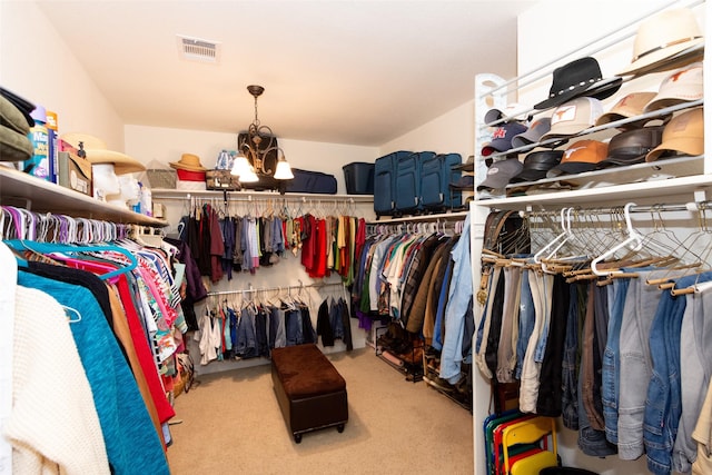 walk in closet featuring a notable chandelier and light colored carpet