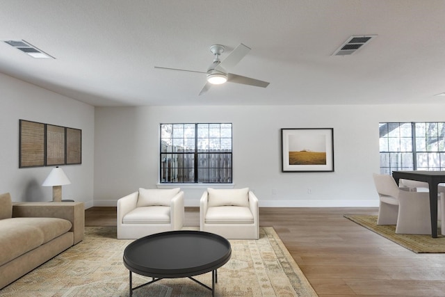 living room featuring ceiling fan, light hardwood / wood-style floors, and plenty of natural light