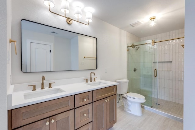 bathroom featuring vanity, a shower with shower door, and toilet