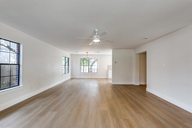 spare room featuring ceiling fan with notable chandelier and light hardwood / wood-style flooring