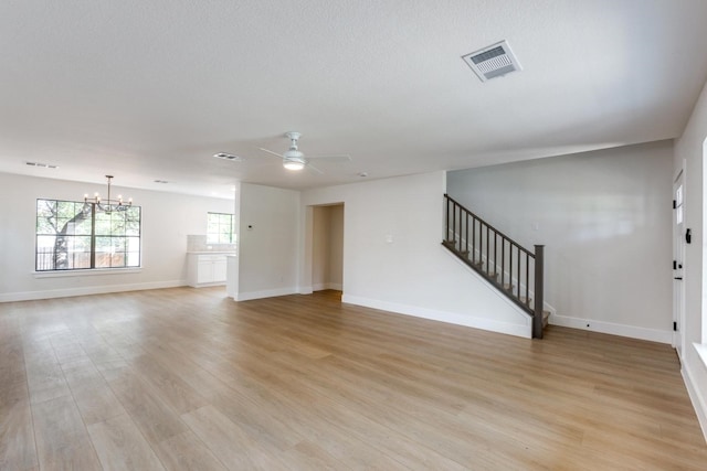 unfurnished living room with ceiling fan with notable chandelier and light wood-type flooring