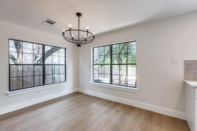 unfurnished dining area featuring a notable chandelier and hardwood / wood-style floors