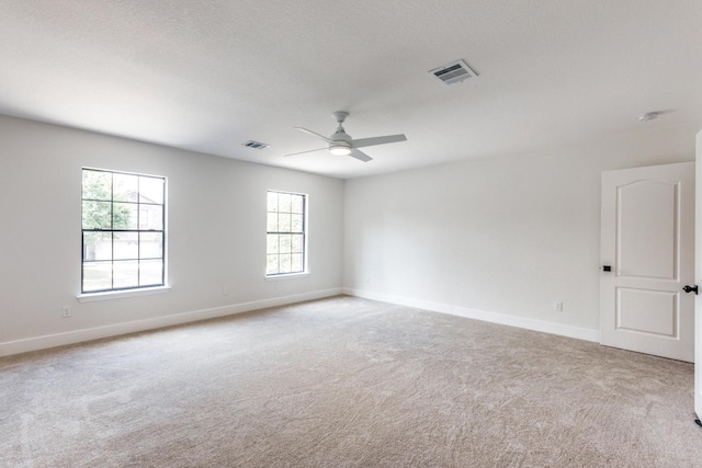 carpeted empty room with ceiling fan and a wealth of natural light