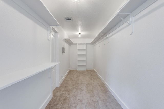 walk in closet featuring light carpet