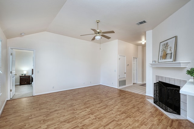 unfurnished living room featuring vaulted ceiling, a fireplace, light wood-type flooring, and ceiling fan