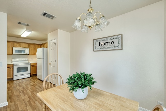 dining area with an inviting chandelier and light hardwood / wood-style flooring