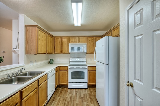 kitchen with white appliances, light wood-type flooring, a textured ceiling, and sink