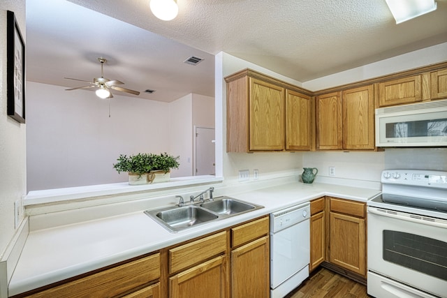 kitchen featuring white appliances, dark wood-type flooring, a textured ceiling, and sink