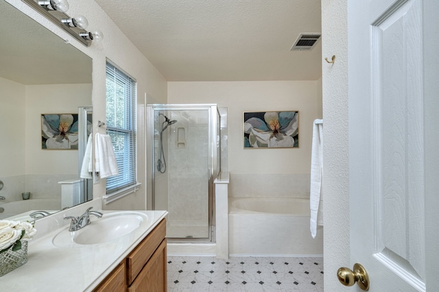 bathroom with a textured ceiling, separate shower and tub, and vanity