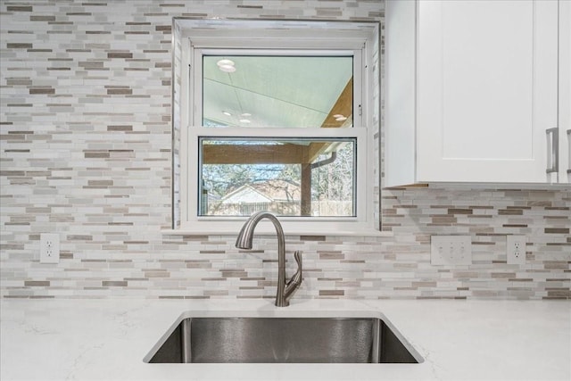 kitchen featuring sink, white cabinets, tasteful backsplash, and light stone counters